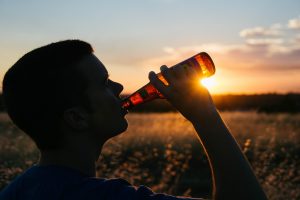 ragazzo che beve bottiglia di birra al tramonto bere sotto antibiotico